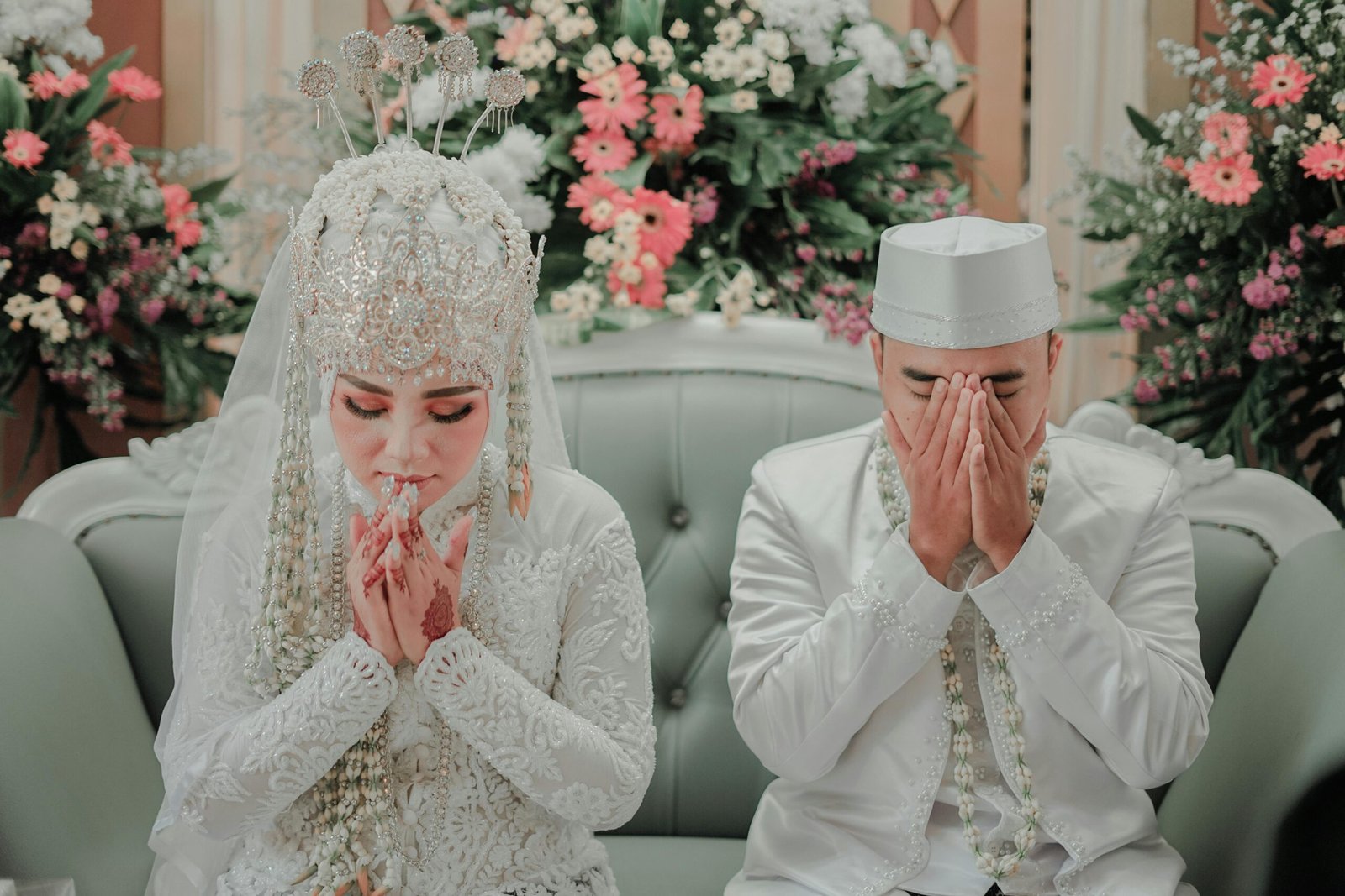 Muslim bride and groom in traditional wedding dress making dua at their nikah ceremony